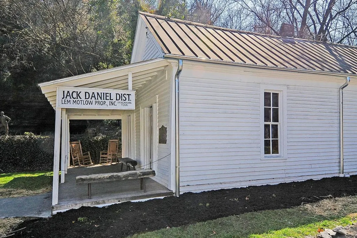 This exterior image highlights the front porch of the Yellow Cottage, adorned with rocking chairs and nestled under the Jack Daniel Distillery sign. The welcoming porch, set against the exterior wall, evokes a classic, nostalgic Southern charm—ideal for relaxing mornings or evenings spent together.